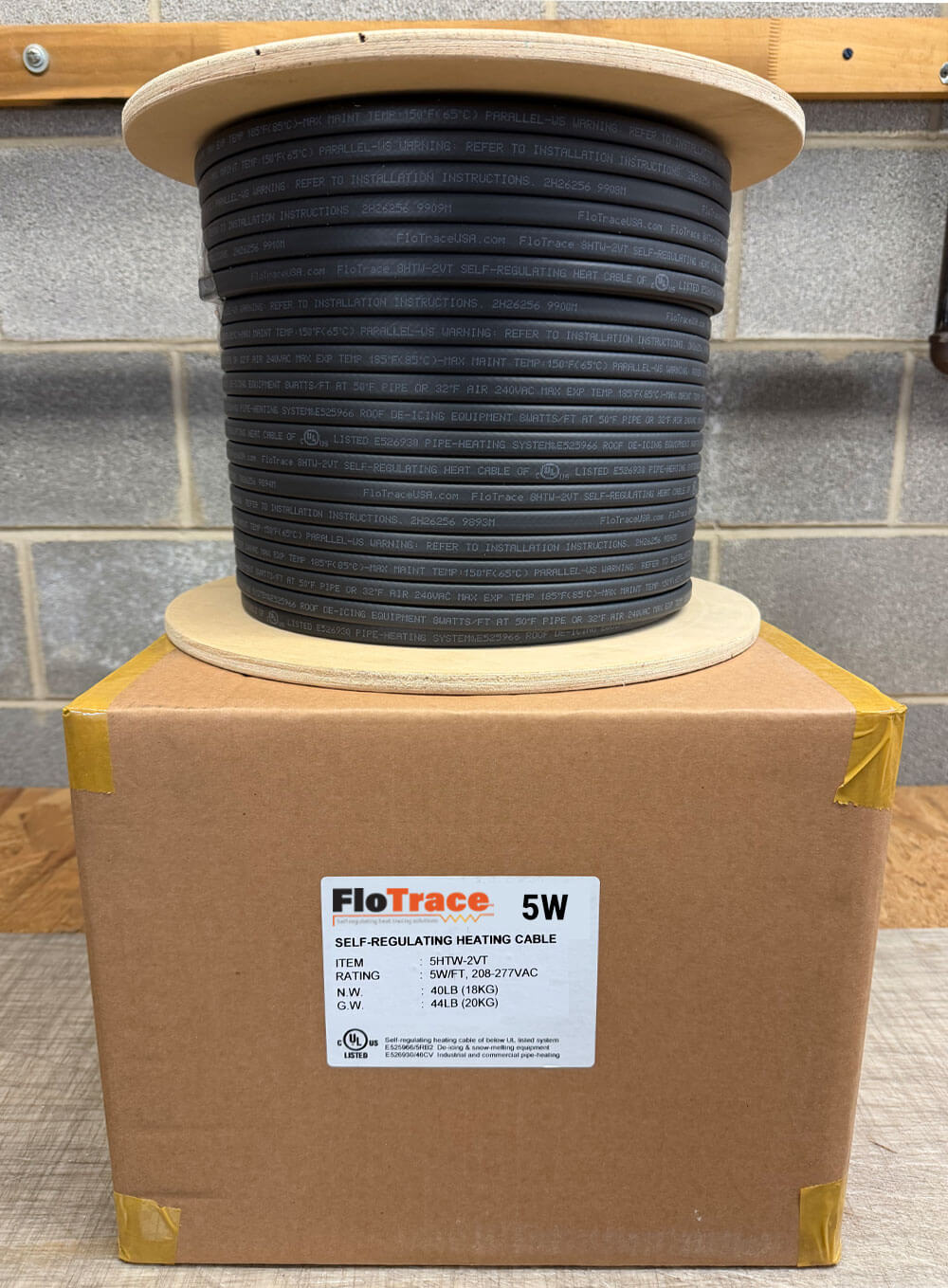 5watt Spool of black self-regulating heat trace cable on abox with FloTrace branding.